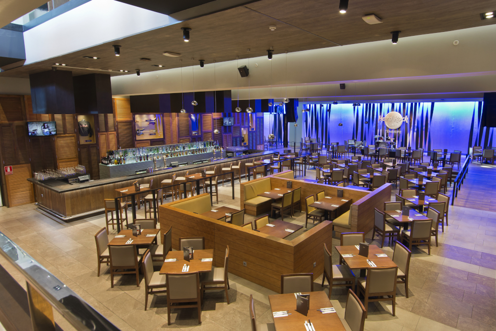 Restaurant at the Hard Rock Café Tenerife with tables and an illuminated bar.