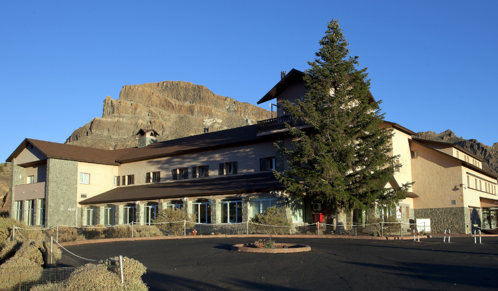 Building with a mountainous background and large tree in El Teide, Tenerife.