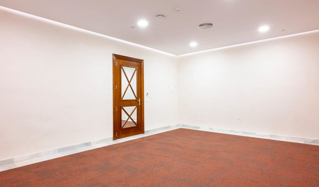 Empty room with wooden door and red carpet in conference center in Tenerife.