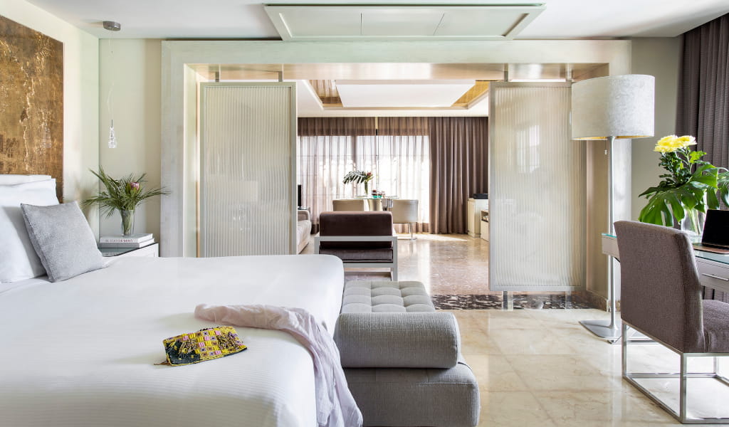 Modern hotel room in Tenerife with bed and living room at the back.