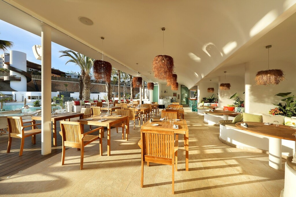 Open-air restaurant with wooden chairs and views of the pool in Tenerife.