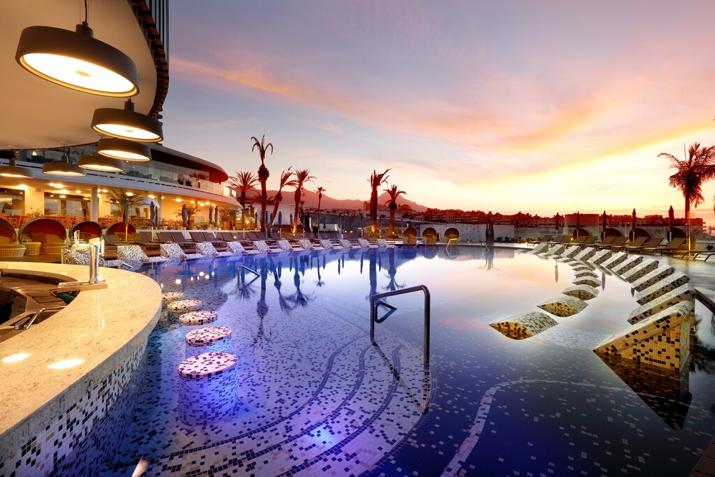 Swimming pool at sunset in a hotel in Tenerife, with modern lighting and sun loungers.