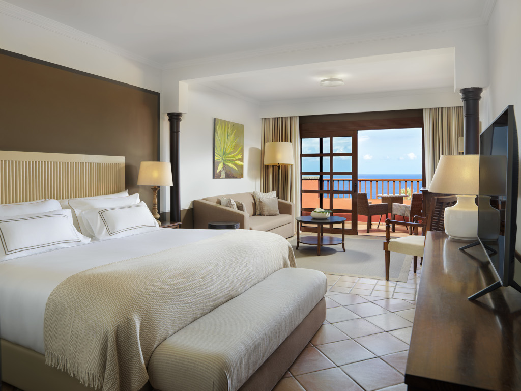 Hotel room in Tenerife with bed, living room and balcony overlooking the sea.