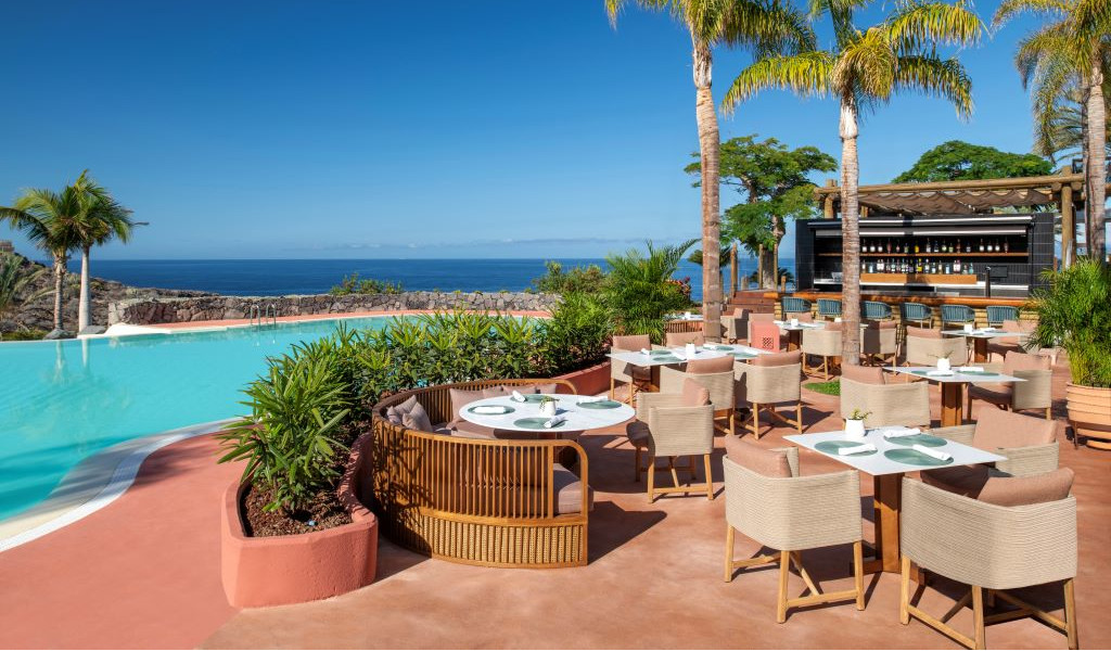Terrace with tables and chairs by the pool and sea views in Tenerife.
