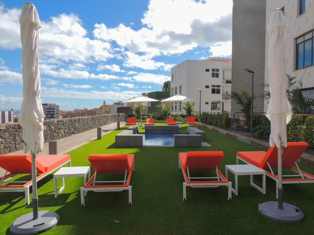 Sun loungers and parasols on a terrace with urban view in Santa Cruz de Tenerife.