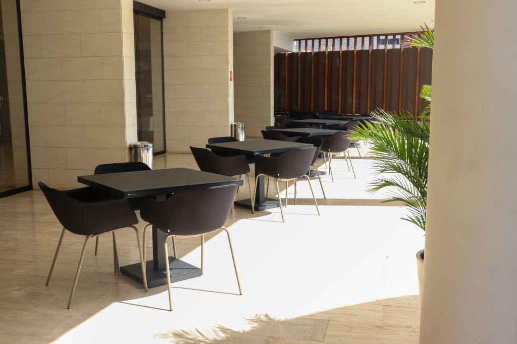 Terrace with black tables and chairs in Tenerife, with natural light and decorative plants.