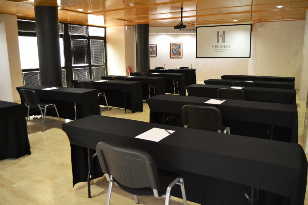 Conference room with black tables, chairs and projection screen in Hecansa, Tenerife.