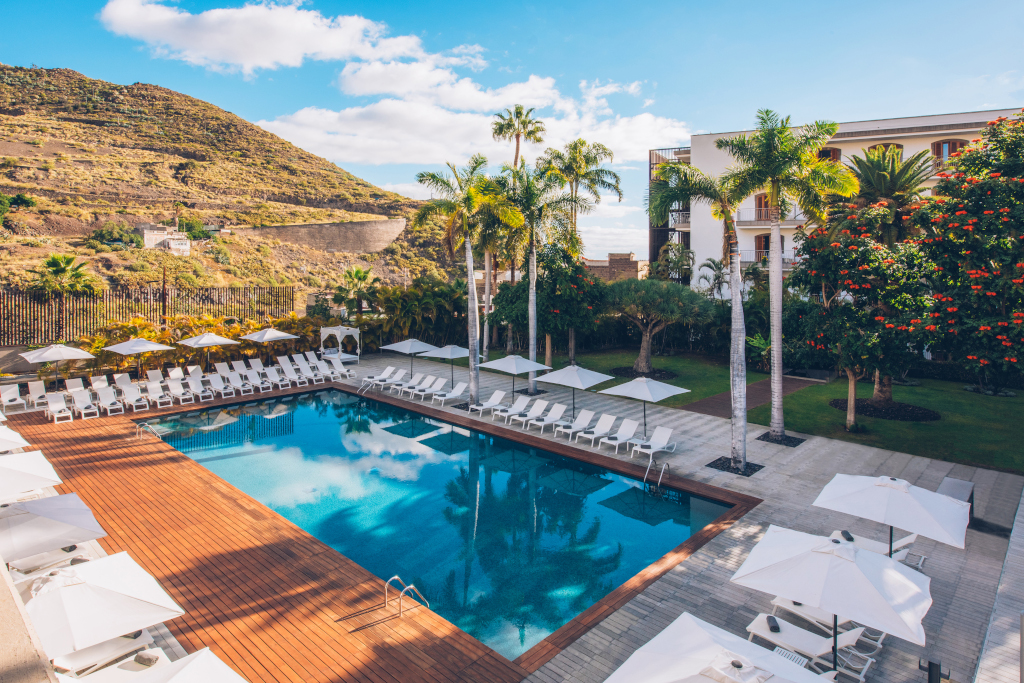 Swimming pool surrounded by sun loungers and parasols, with mountains in the background in Tenerife.