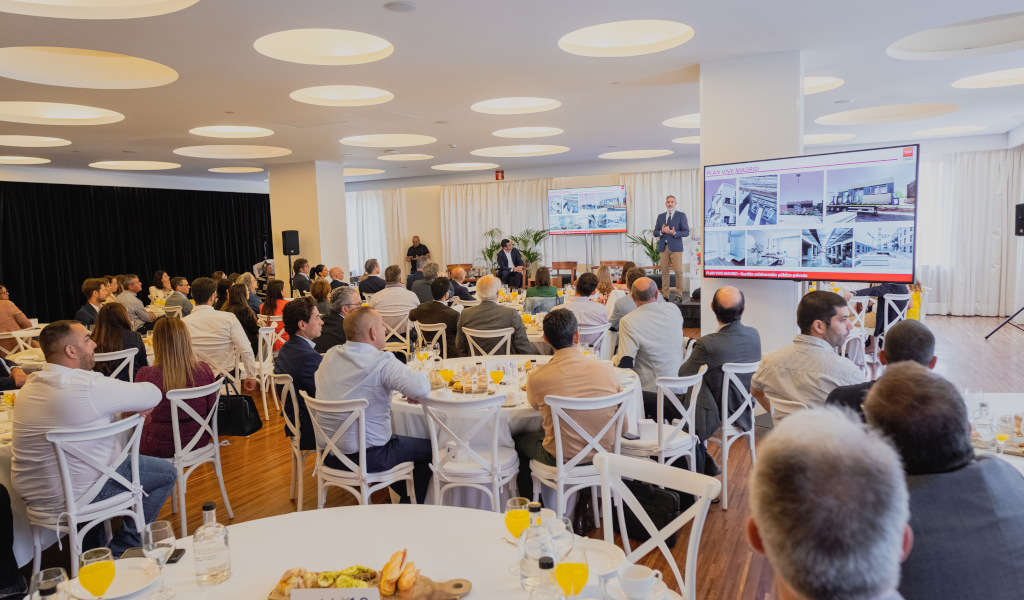 People at conference watch presenter and big screens in Tenerife.