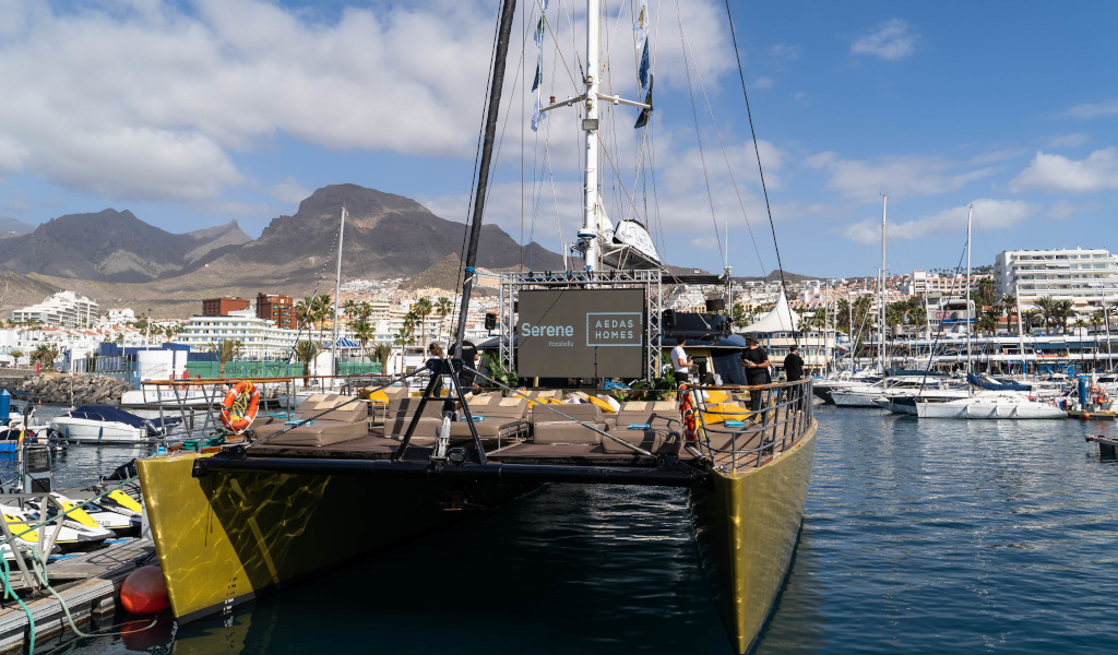 Catamaran docked in marina in Los Cristianos, Tenerife, with mountains in the background.