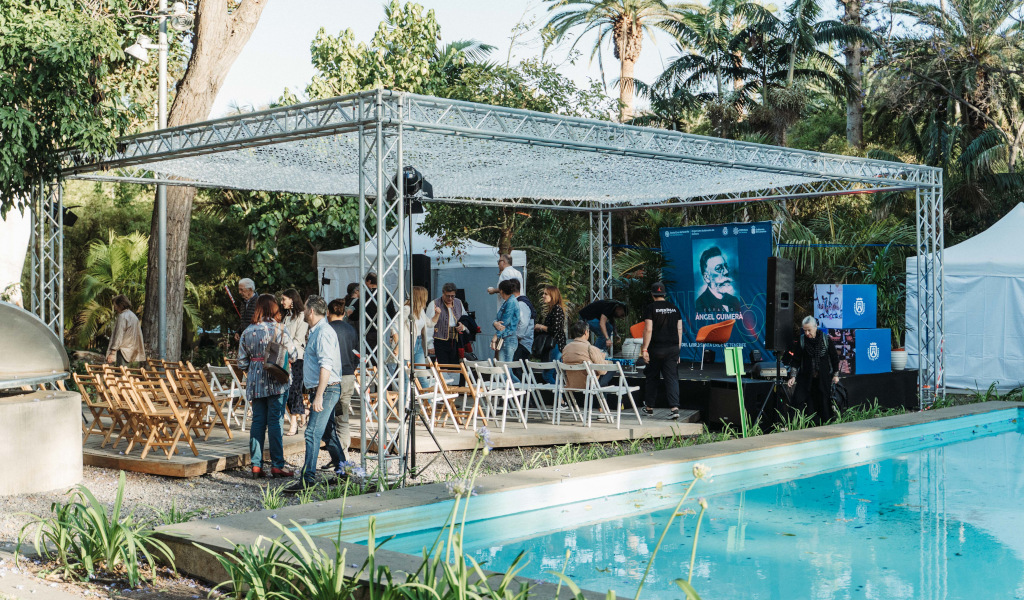 Event in a garden in Tenerife with seating and a sign by Ángel Guimerá near a swimming pool.