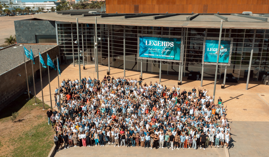 Large group of people gathered in front of a building with a LEGENDS never give up sign.
