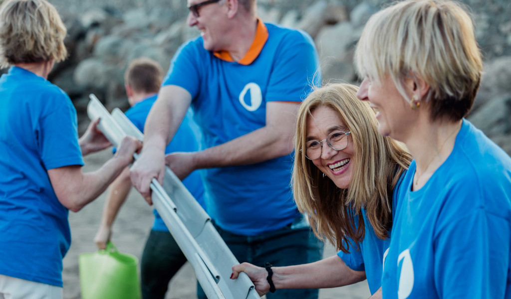 People in blue T-shirts collaborate in an activity on the beach in Tenerife.