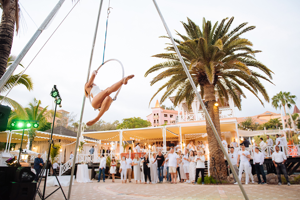 Aerial performer at outdoor event beneath palm trees in Tenerife.