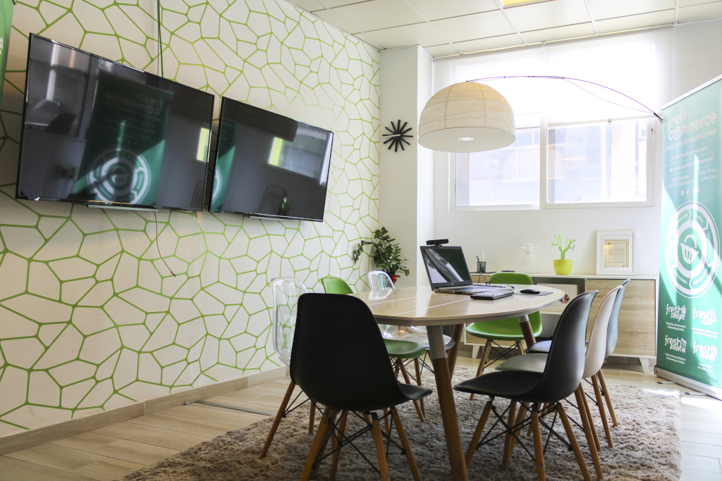 Meeting room with two screens, modern decor, and E-commerce banner in Tenerife.