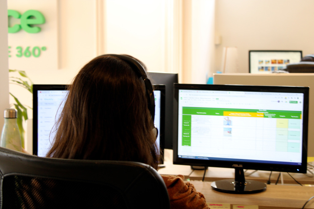 Person using headphones working at a computer with spreadsheet open, office in Tenerife.