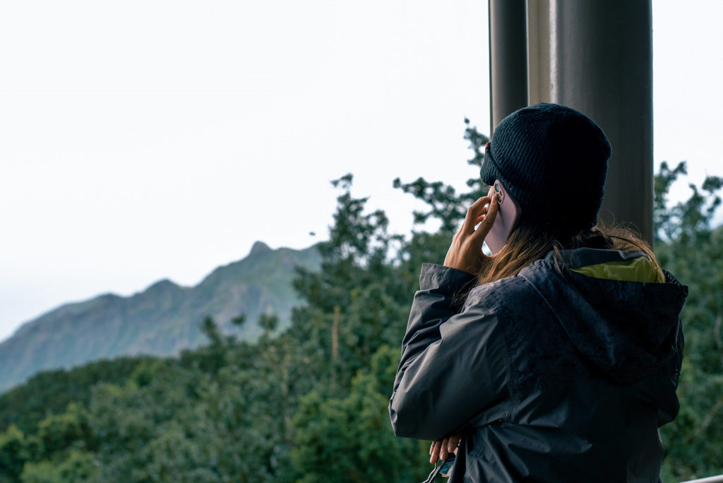 Person talking on a mobile phone with mountains and trees in Tenerife background.