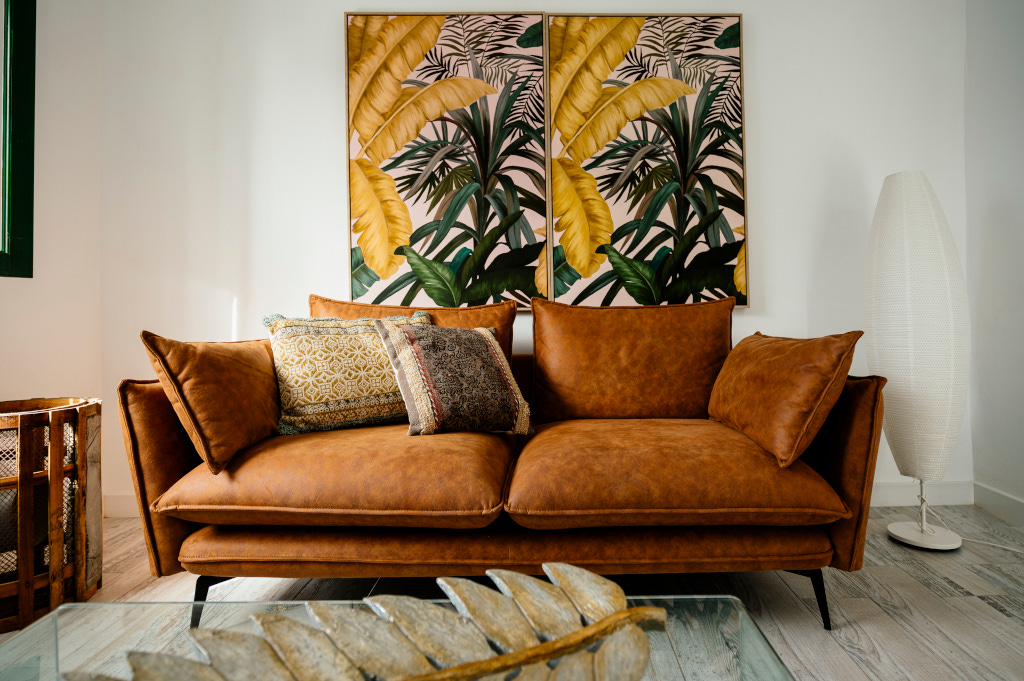 Brown leather sofa with patterned cushions in front of botanical art in Tenerife room.