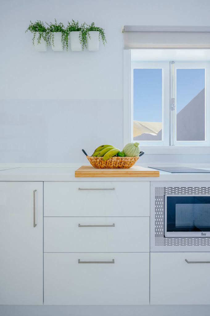 Basket with fruit on kitchen counter, plants above, and window view in Tenerife.