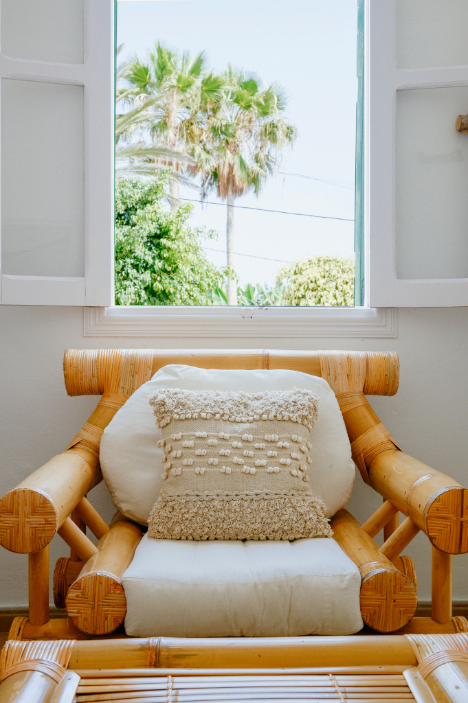 Bamboo chair with textured cushion by an open window with palm trees in Tenerife.
