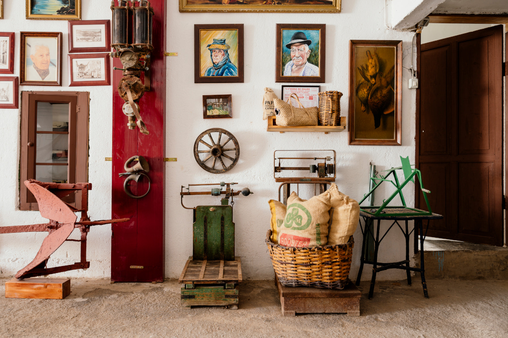 Antique farm tools and vintage paintings displayed on a wall in Tenerife.
