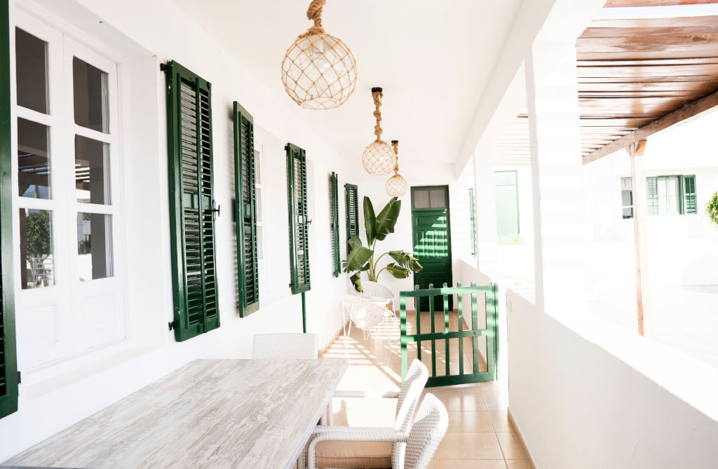 Dining table on a Tenerife terrace with green shutters and hanging lamps.