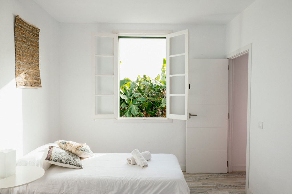 Bedroom with open window overlooking greenery in Tenerife.