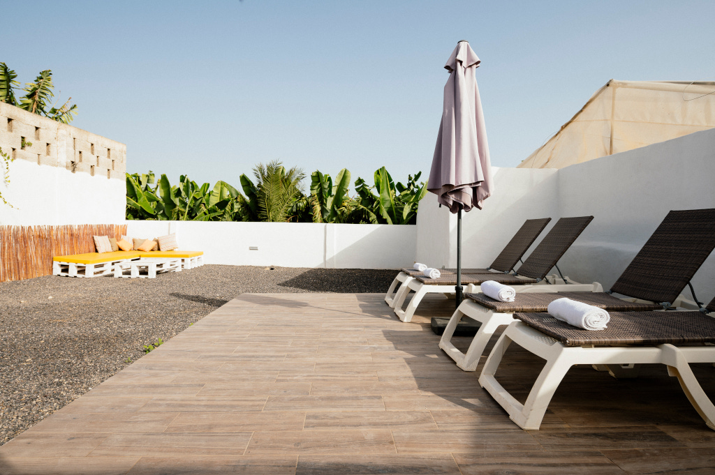 Sun loungers and umbrella on a patio surrounded by banana trees in Tenerife.