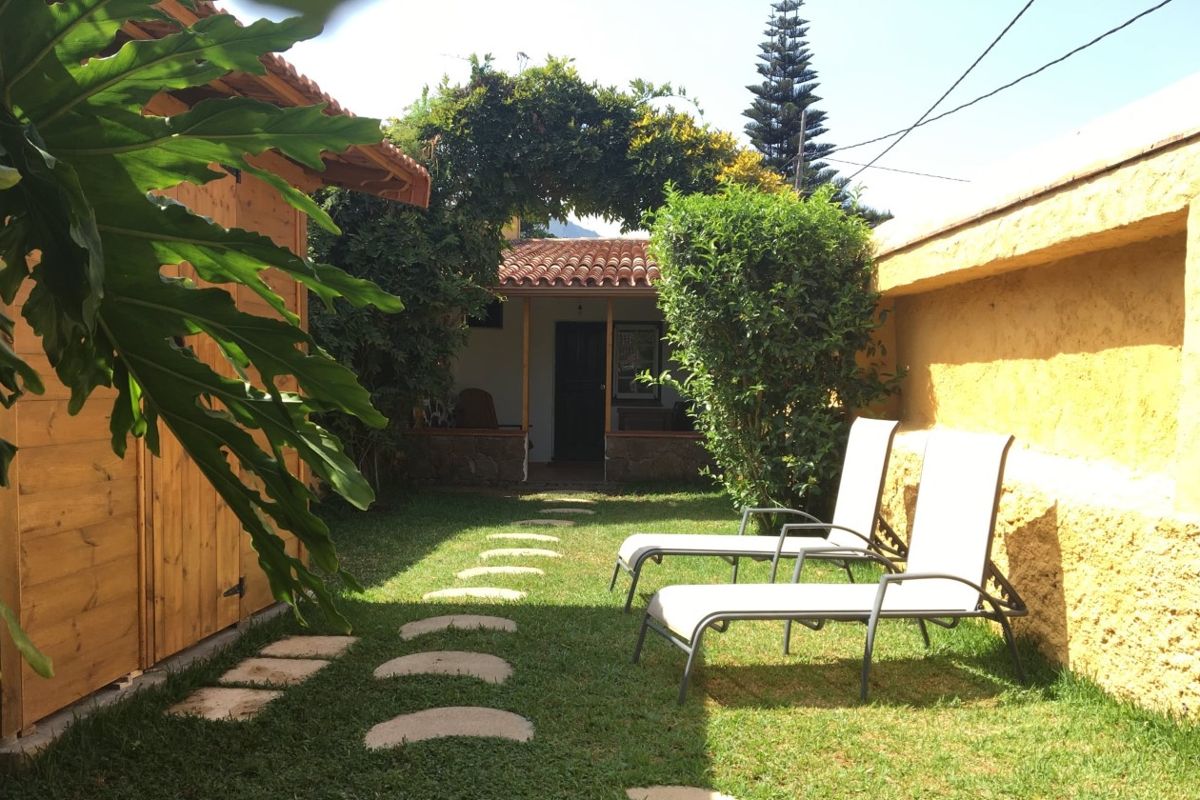 Two lounge chairs on a garden path leading to a house in Tenerife.