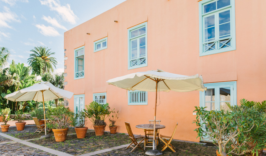 Orange building with blue windows, patio tables, and umbrellas in Tenerife.