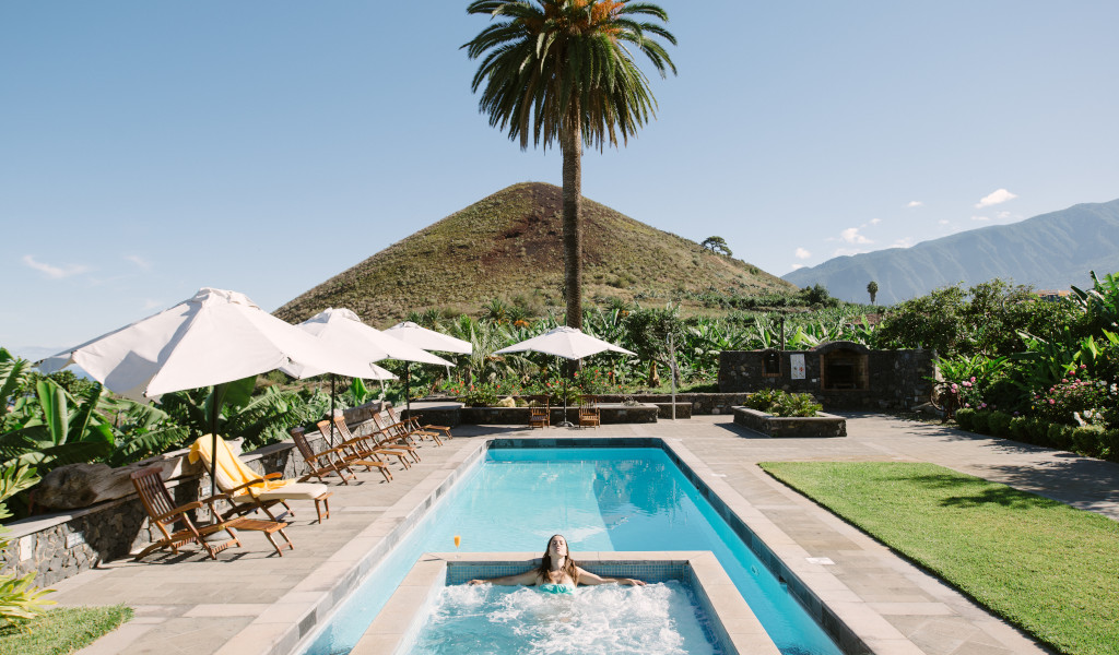 Pool with sun loungers and umbrellas in a Tenerife garden setting.