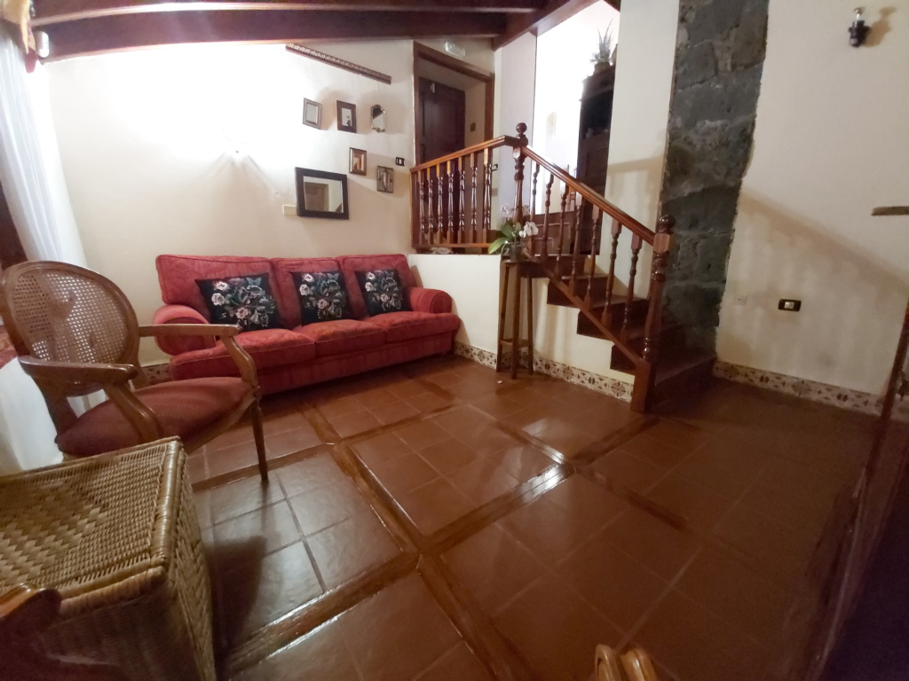 Living room with red couch, wooden staircase, and decorative items in Tenerife.