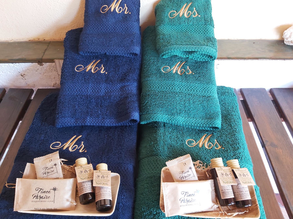 Blue and green embroidered towels with toiletries labeled Finca Paraíso.