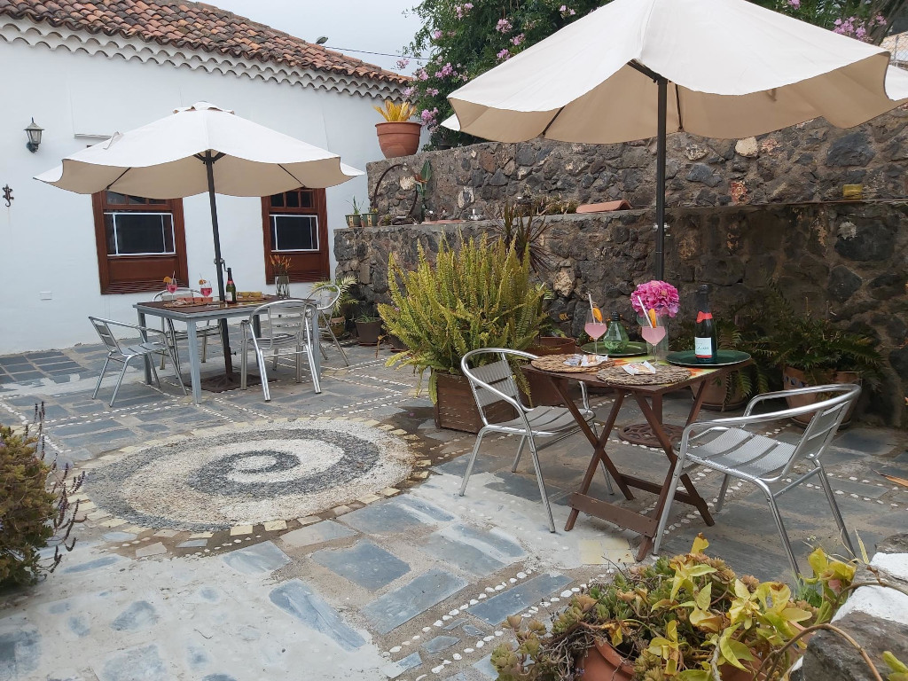 Outdoor patio with tables, chairs, umbrellas, and plants in Tenerife.