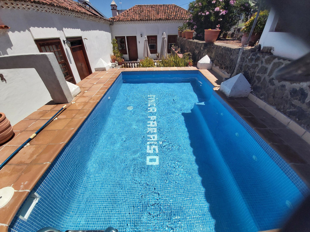 Outdoor pool with FINCA PARAÍSO on the bottom, surrounded by a stone patio in Tenerife.