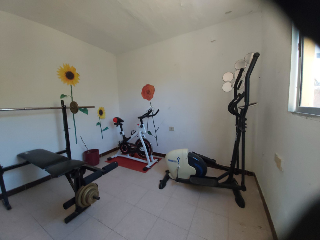 Home gym in Tenerife with exercise bike, bench press, and elliptical.