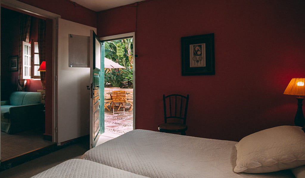 Bedroom with open door to garden patio, wooden chairs, in Tenerife.