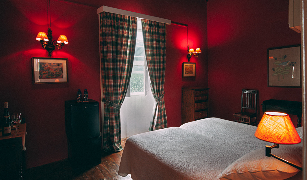 Twin bedroom with red walls, plaid curtains, and lamps in Tenerife.
