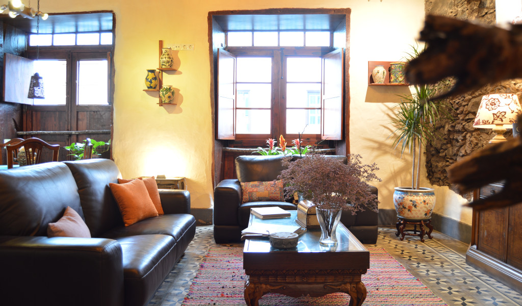 Living room with leather sofas, plants, and wooden table in a traditional Tenerife house.