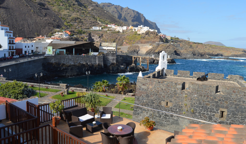 Coastal view of Garachico, Tenerife, with a historic fort and surrounding town buildings.