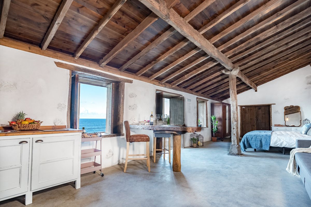 Spacious wooden-beamed room overlooking ocean in Tenerife with kitchen and bed.