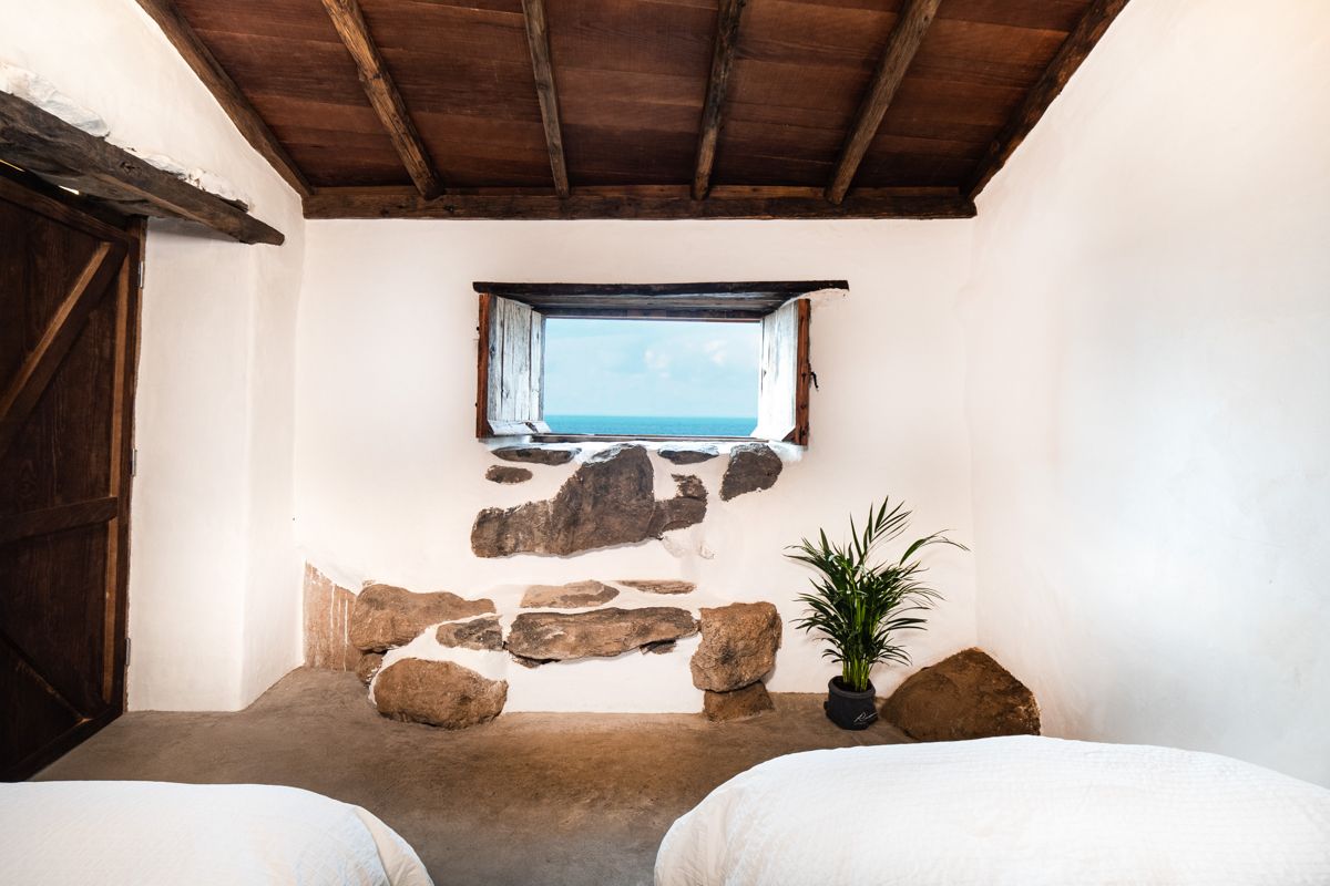 Rustic room with ocean view window and plant in Tenerife.