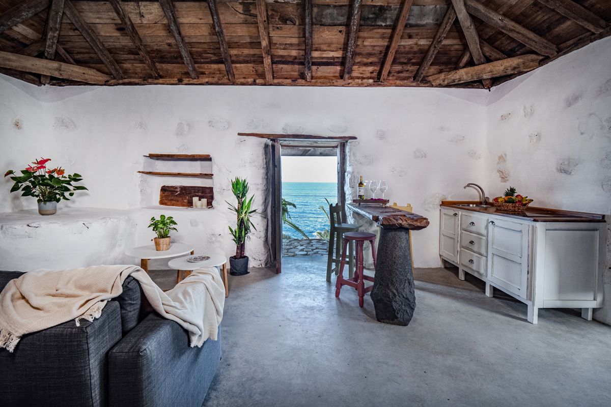 Rustic cottage interior in Tenerife with ocean view through the door.