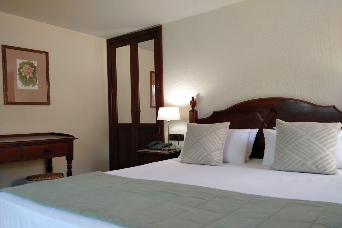 Hotel room in Tenerife with a double bed, pillows, a lamp, and a wooden desk.