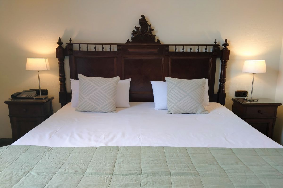 King-sized bed with wooden headboard, two pillows, and bedside tables in Tenerife hotel room.