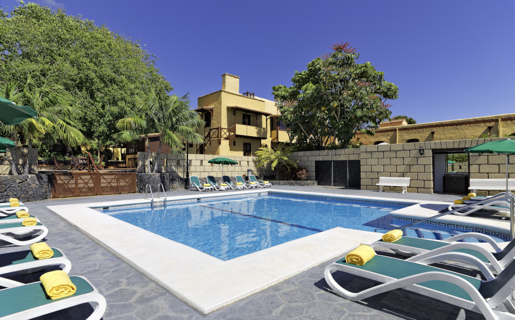 Outdoor pool with sun loungers and umbrellas at a villa in Tenerife.