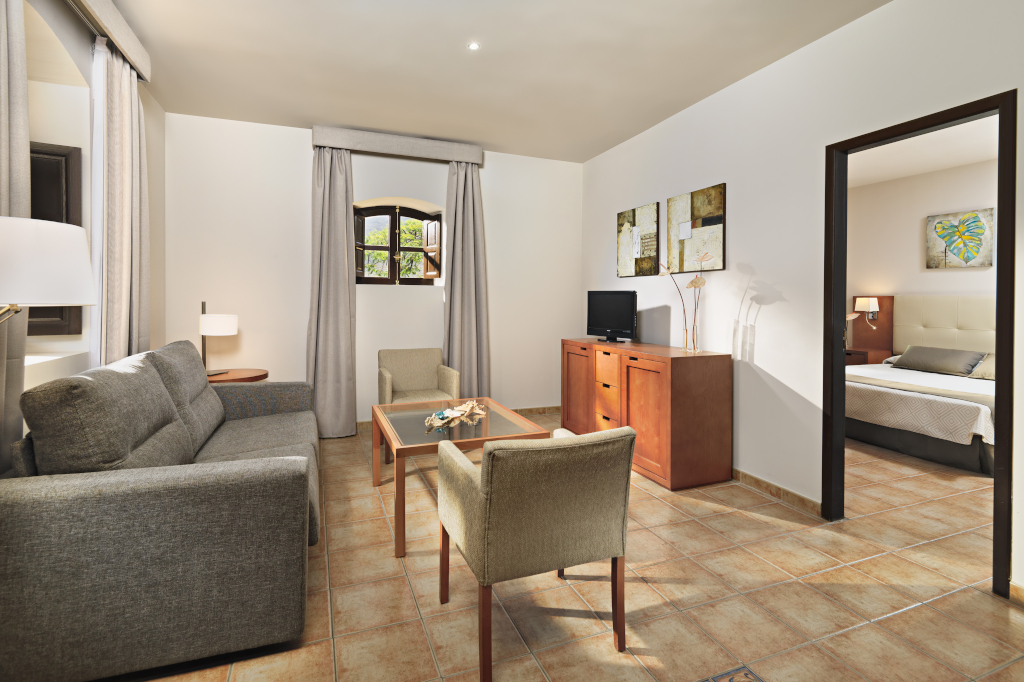 Living room with sofa, chairs, TV, and view into bedroom in Tenerife accommodation.