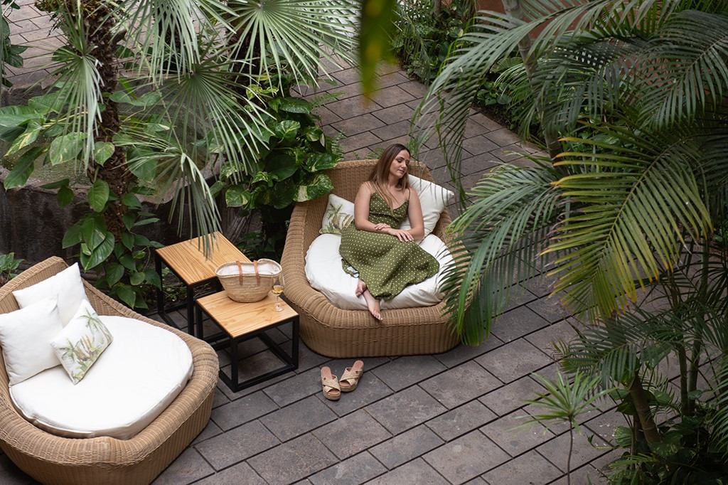Woman relaxing on patio amidst tropical plants in Tenerife.