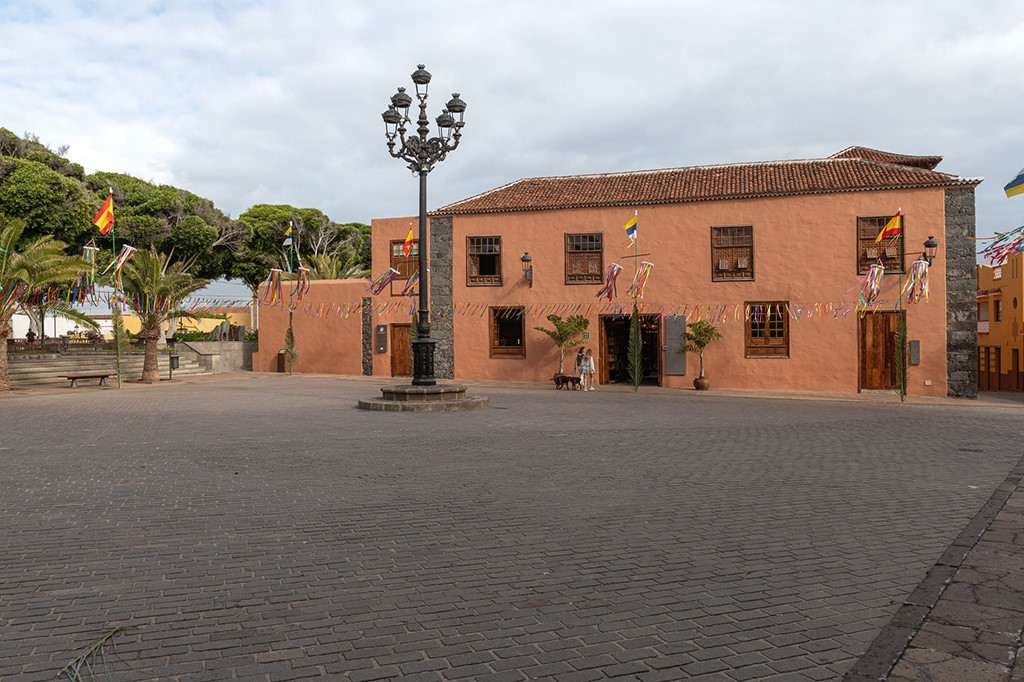 Town square with flags, a historic building, and a streetlamp in Tenerife.