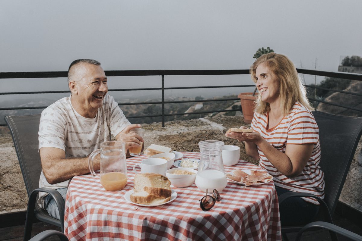 Couple enjoying breakfast on a terrace in Tenerife with orange juice and bread.